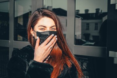 Kız, yüzünde koruyucu steril tıbbi maske takan genç bir kadın Asya sokak gösterilerinde, avuçlarında, ellerinde kameralara bakıyor. Hava kirliliği, virüs, Çin salgını koronavirüs konsepti.