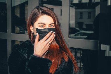 Kız, yüzünde koruyucu steril tıbbi maske takan genç bir kadın Asya sokak gösterilerinde, avuçlarında, ellerinde kameralara bakıyor. Hava kirliliği, virüs, Çin salgını koronavirüs konsepti.