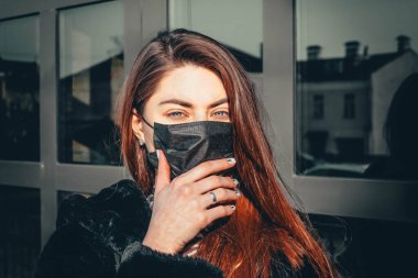 Kız, yüzünde koruyucu steril tıbbi maske takan genç bir kadın Asya sokak gösterilerinde, avuçlarında, ellerinde kameralara bakıyor. Hava kirliliği, virüs, Çin salgını koronavirüs konsepti.