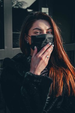 Kız, yüzünde koruyucu steril tıbbi maske takan genç bir kadın Asya sokak gösterilerinde, avuçlarında, ellerinde kameralara bakıyor. Hava kirliliği, virüs, Çin salgını koronavirüs konsepti.