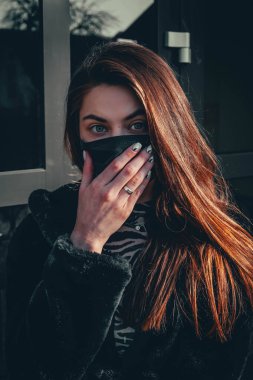 Kız, yüzünde koruyucu steril tıbbi maske takan genç bir kadın Asya sokak gösterilerinde, avuçlarında, ellerinde kameralara bakıyor. Hava kirliliği, virüs, Çin salgını koronavirüs konsepti.