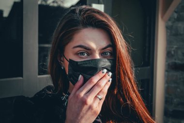 Kız, yüzünde koruyucu steril tıbbi maske takan genç bir kadın Asya sokak gösterilerinde, avuçlarında, ellerinde kameralara bakıyor. Hava kirliliği, virüs, Çin salgını koronavirüs konsepti.