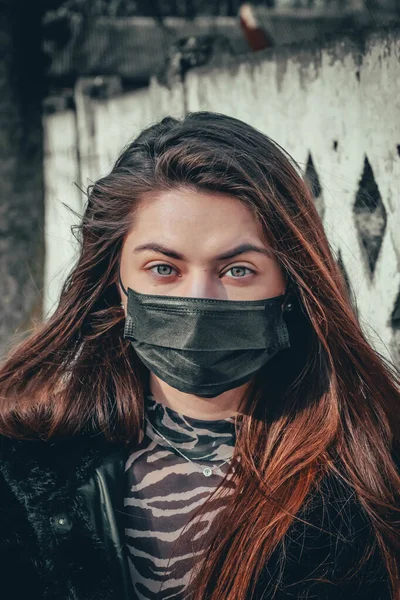 Girl, young woman in protective sterile medical mask on her face looking at camera outdoors, on asian street show palm, hand, stop no sign. Air pollution, virus, Chinese pandemic coronavirus concept.