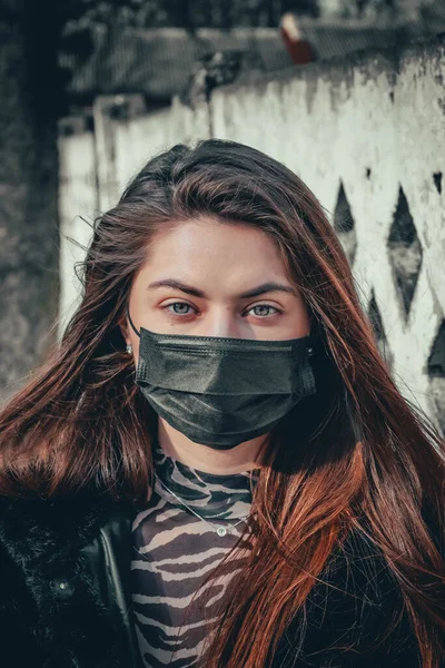 Girl, young woman in protective sterile medical mask on her face looking at camera outdoors, on asian street show palm, hand, stop no sign. Air pollution, virus, Chinese pandemic coronavirus concept.