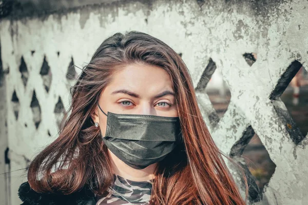 Kız, yüzünde koruyucu steril tıbbi maske takan genç bir kadın Asya sokak gösterilerinde, avuçlarında, ellerinde kameralara bakıyor. Hava kirliliği, virüs, Çin salgını koronavirüs konsepti.