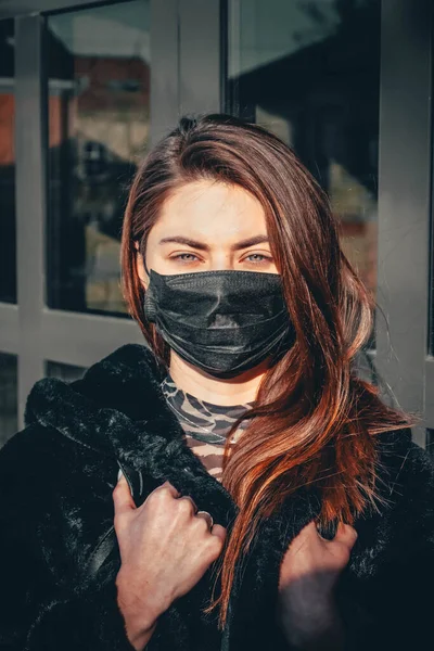 Kız, yüzünde koruyucu steril tıbbi maske takan genç bir kadın Asya sokak gösterilerinde, avuçlarında, ellerinde kameralara bakıyor. Hava kirliliği, virüs, Çin salgını koronavirüs konsepti.