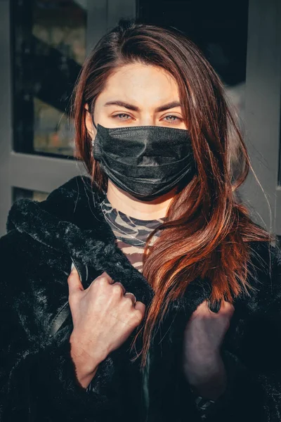 Kız, yüzünde koruyucu steril tıbbi maske takan genç bir kadın Asya sokak gösterilerinde, avuçlarında, ellerinde kameralara bakıyor. Hava kirliliği, virüs, Çin salgını koronavirüs konsepti.