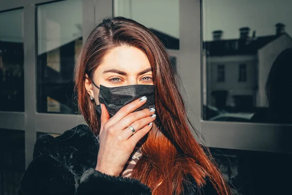 Girl, young woman in protective sterile medical mask on her face looking at camera outdoors, on asian street show palm, hand, stop no sign. Air pollution, virus, Chinese pandemic coronavirus concept.