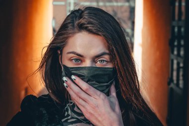 Kız, yüzünde koruyucu steril tıbbi maske takan genç bir kadın Asya sokak gösterilerinde, avuçlarında, ellerinde kameralara bakıyor. Hava kirliliği, virüs, Çin salgını koronavirüs konsepti.