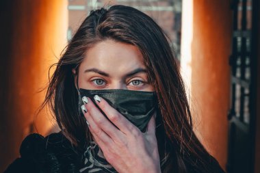 Kız, yüzünde koruyucu steril tıbbi maske takan genç bir kadın Asya sokak gösterilerinde, avuçlarında, ellerinde kameralara bakıyor. Hava kirliliği, virüs, Çin salgını koronavirüs konsepti.