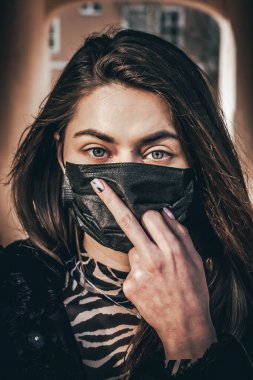 Kız, yüzünde koruyucu steril tıbbi maske takan genç bir kadın Asya sokak gösterilerinde, avuçlarında, ellerinde kameralara bakıyor. Hava kirliliği, virüs, Çin salgını koronavirüs konsepti.