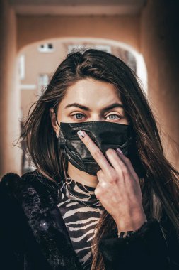 Kız, yüzünde koruyucu steril tıbbi maske takan genç bir kadın Asya sokak gösterilerinde, avuçlarında, ellerinde kameralara bakıyor. Hava kirliliği, virüs, Çin salgını koronavirüs konsepti.