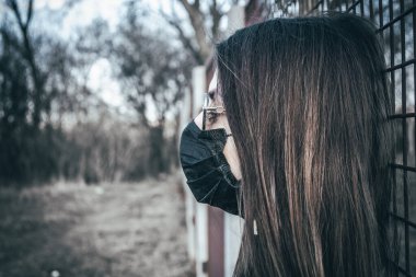 Esmer bir kız sokakta tıbbi bir maskeyle yürüyor, enfeksiyondan korkuyor..