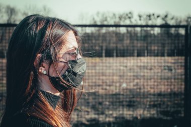 Esmer bir kız sokakta tıbbi bir maskeyle yürüyor, enfeksiyondan korkuyor..