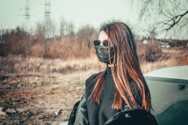 Esmer bir kız sokakta tıbbi bir maskeyle yürüyor, enfeksiyondan korkuyor..