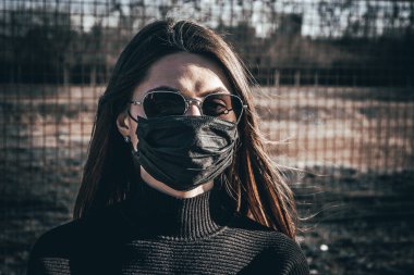 Esmer bir kız sokakta tıbbi bir maskeyle yürüyor, enfeksiyondan korkuyor..