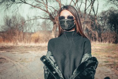 Esmer bir kız sokakta tıbbi bir maskeyle yürüyor, enfeksiyondan korkuyor..