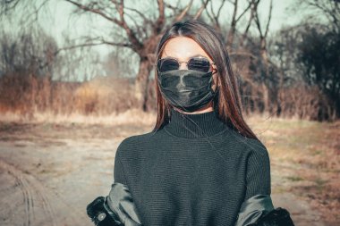 Esmer bir kız sokakta tıbbi bir maskeyle yürüyor, enfeksiyondan korkuyor..