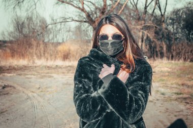 Esmer bir kız sokakta tıbbi bir maskeyle yürüyor, enfeksiyondan korkuyor..
