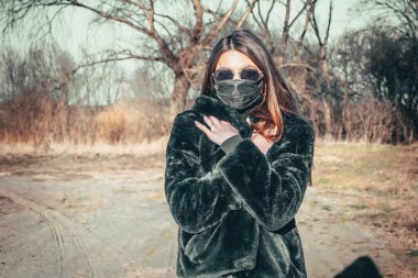 Esmer bir kız sokakta tıbbi bir maskeyle yürüyor, enfeksiyondan korkuyor..