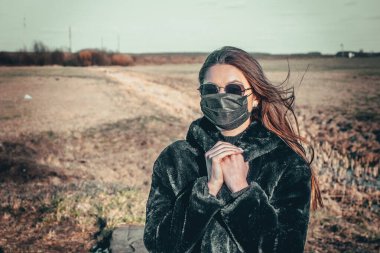 Esmer bir kız sokakta tıbbi bir maskeyle yürüyor, enfeksiyondan korkuyor..