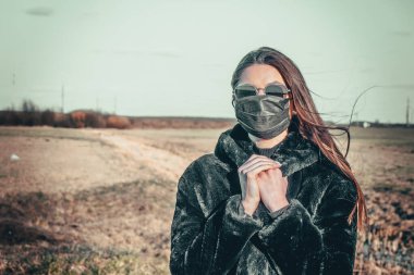 Esmer bir kız sokakta tıbbi bir maskeyle yürüyor, enfeksiyondan korkuyor..