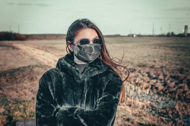 Esmer bir kız sokakta tıbbi bir maskeyle yürüyor, enfeksiyondan korkuyor..