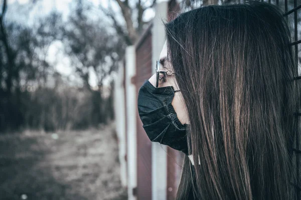 Esmer bir kız sokakta tıbbi bir maskeyle yürüyor, enfeksiyondan korkuyor..