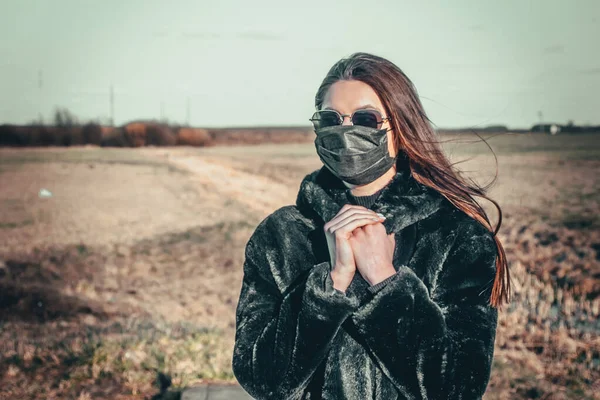 Esmer bir kız sokakta tıbbi bir maskeyle yürüyor, enfeksiyondan korkuyor..