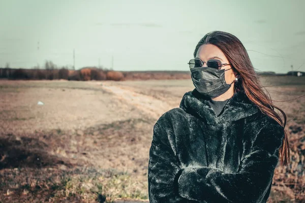 Esmer bir kız sokakta tıbbi bir maskeyle yürüyor, enfeksiyondan korkuyor..