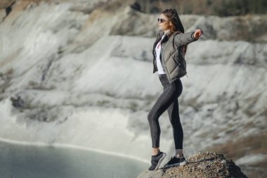 Gölün kıyısında siyah pantolon ve deri ceket giymiş güzel bir genç kız.