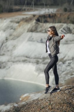 Gölün kıyısında siyah pantolon ve deri ceket giymiş güzel bir genç kız.