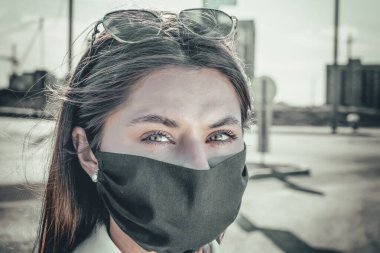 Yüz maskesi takan, kameraya bakan genç bir kadının portresi. Grip salgını, toz alerjisi, virüse karşı koruma. Şehir hava kirliliği kavramı