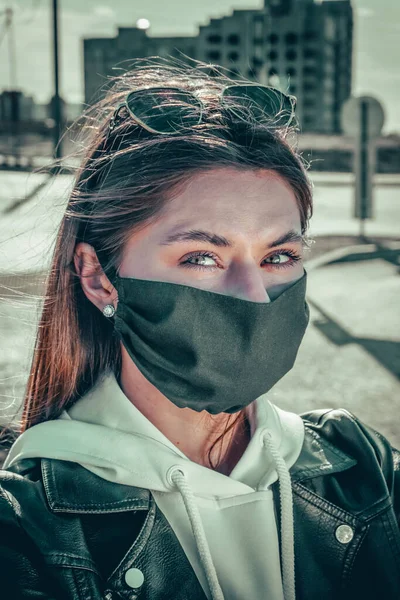 portrait of young woman wearing a face mask, looking at camera, close up. Flu epidemic, dust allergy, protection against virus. City air pollution concept