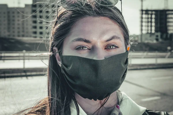 portrait of young woman wearing a face mask, looking at camera, close up. Flu epidemic, dust allergy, protection against virus. City air pollution concept