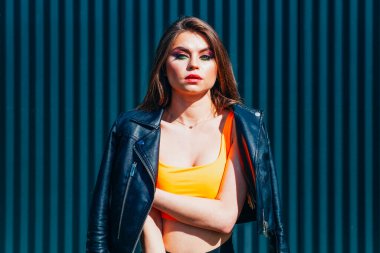 Siyah arka planda parlak makyajlı bir güzellik var. O, siyah bir ceket ve kısa bir etek giydi, külotlu çorabı üzerinde bir ağ ve beyaz spor ayakkabıları vardı..