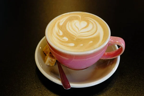 カプチーノカップコーヒーのハート柄ピンクカップ黒の背景 — ストック写真