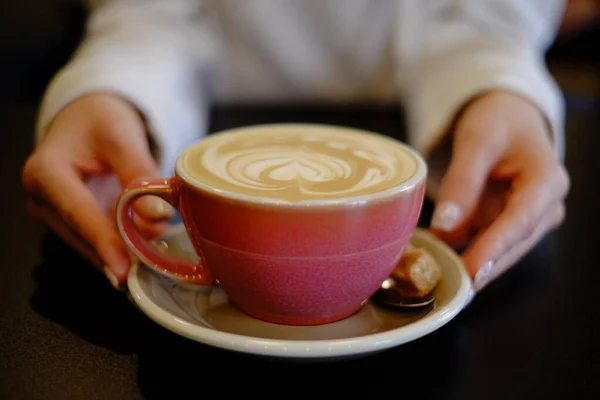 カフェでカプチーノを飲みながら心を込めてコーヒーを飲みながらピンク色のカップでコーヒーを飲みながら — ストック写真