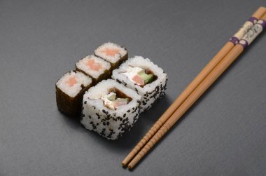 suşi yemek çubukları ile siyah tabloda