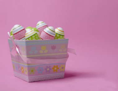 Kağıt sepeti pastel renkler pembe bir arka plan üzerinde renkli Paskalya yumurta. Paskalya Tema.