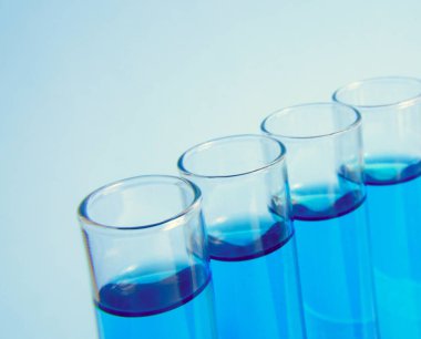 Mavi sıvı, makro ve seçici odaklı test cam tüpleri. Laboratuvar test tüpleri. Açık mavi arka planda sıvı numuneli test tüpü, yakın plan. Tıbbi konsept. 