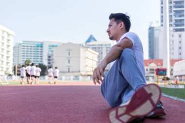 Spor stadyumunda gerinen atletik bir adamın tam boy portresi..