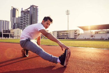 Spor stadyumunda gerinen atletik bir adamın tam boy portresi..