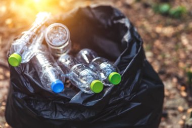 Plastik şişe, yerdeki siyah plastik çöpler..
