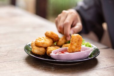 Tavuk Nuggets bir çatal ve Dip sos üzerine kazıklı. Bir kadın Nuggets yemek.