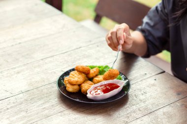 Tavuk Nuggets bir çatal ve Dip sos üzerine kazıklı. Bir kadın Nuggets yemek.