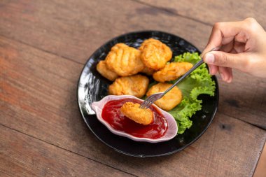 Tavuk Nuggets bir çatal ve Dip sos üzerine kazıklı. Bir kadın Nuggets yemek.