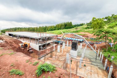 Yağmur bulutu altında inşaat alanında çalışan insanlar.