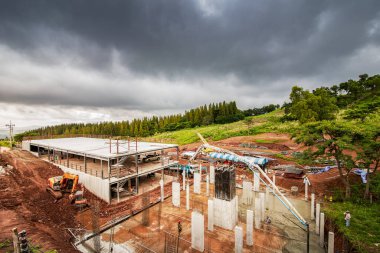 Yağmur bulutu altında inşaat alanında çalışan insanlar.