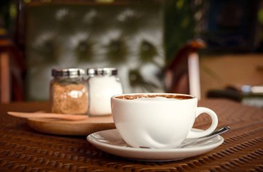 Sıcak bir fincan kahve, sabah yakınındaki ahşap masada..